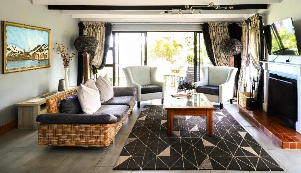 Spacious lounge with wicker seating, cream chairs, and sliding doors opening to garden