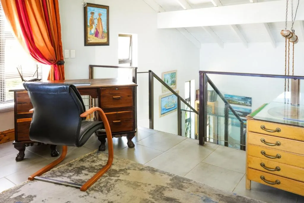 Upstairs lounge with vintage furniture, colorful curtains, and coastal artwork