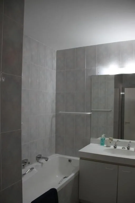 Modern bathroom with gray tiled walls, bathtub, and vanity sink