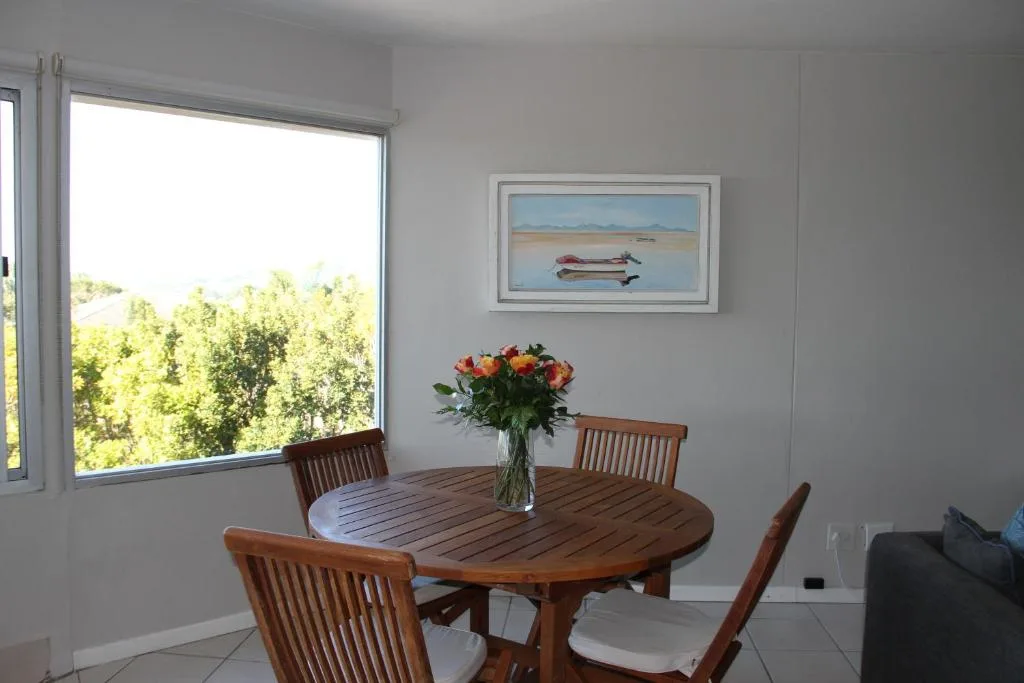 Dining area with wooden table, four chairs, and fresh flowers indoors