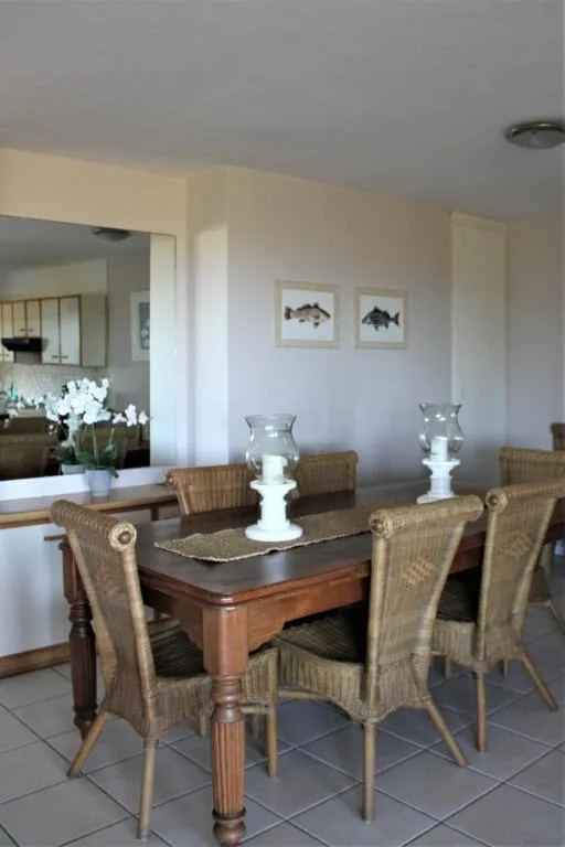 Dining room with wooden table, woven chairs, and coastal decor
