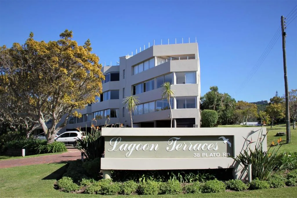 Modern apartment building with signage, palm trees, and manicured gardens