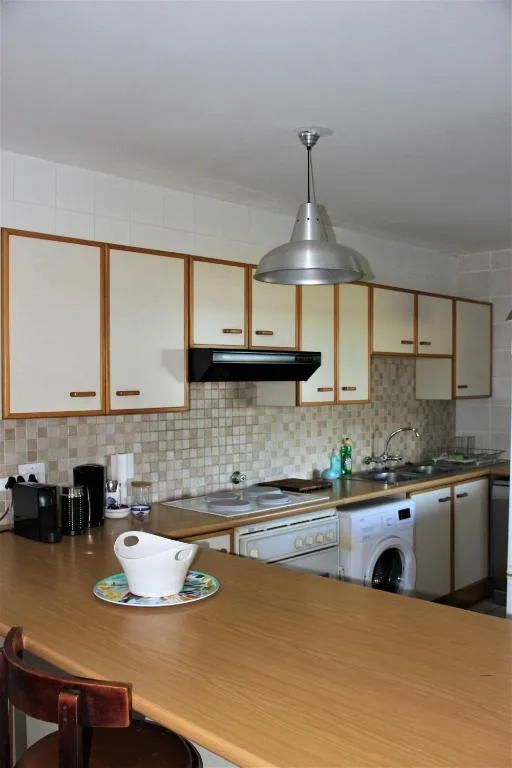 Modern kitchen with wooden cabinetry, tiled backsplash, and pendant lighting