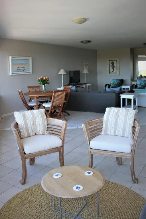 Open-plan lounge with wooden chairs, round table, and dining area beyond