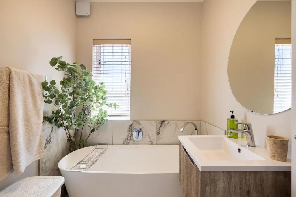 Modern bathroom with freestanding tub, double vanity, and round mirror