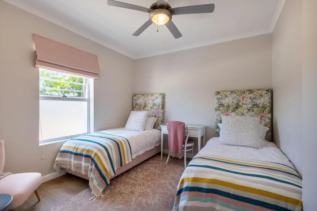 Twin bedroom with floral headboards and striped blankets, ceiling fan overhead