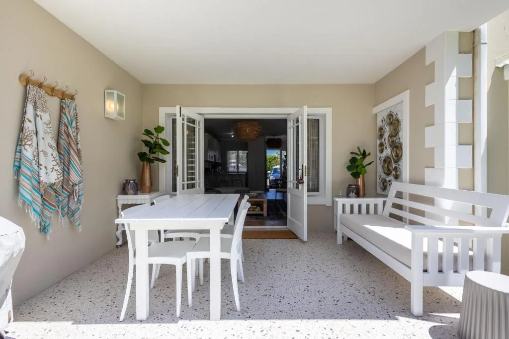 Covered patio with white furniture and ocean views, leading to lounge area
