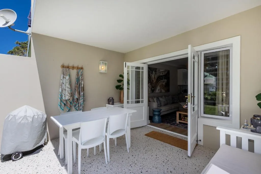 Covered patio with white dining table, chairs, and open sliding doors to lounge