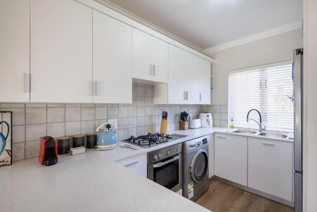 Modern kitchen with white cabinetry, gas stove, washing machine, and sink