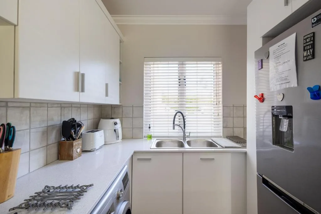 Bright kitchen with white cabinetry, stainless steel sink and black fridge