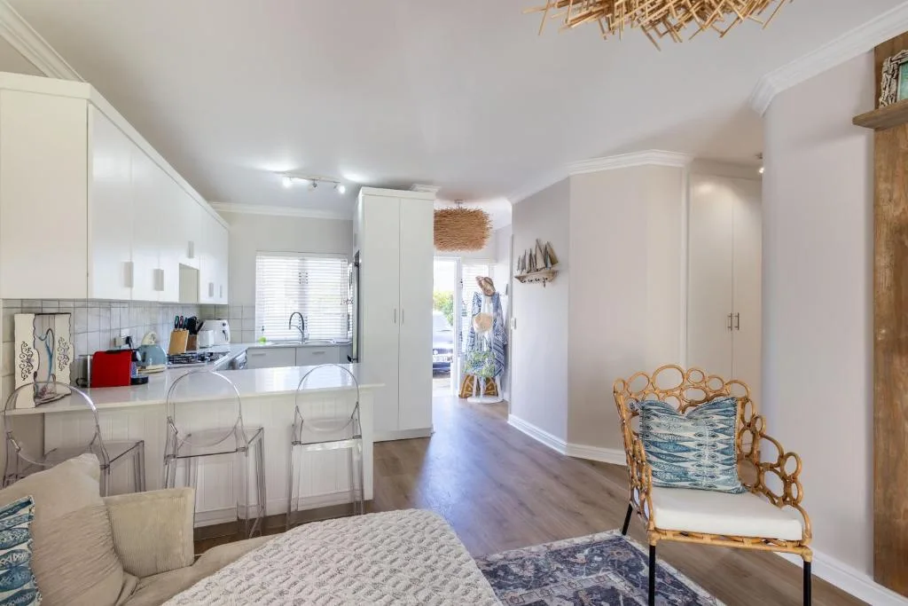 Modern white kitchen with island seating and open-plan living area