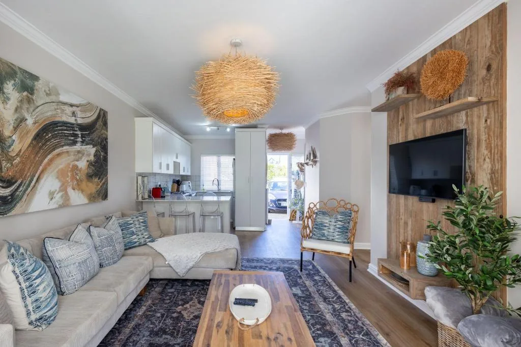 Modern living room with beige sofa, TV, wooden accents, and coastal décor