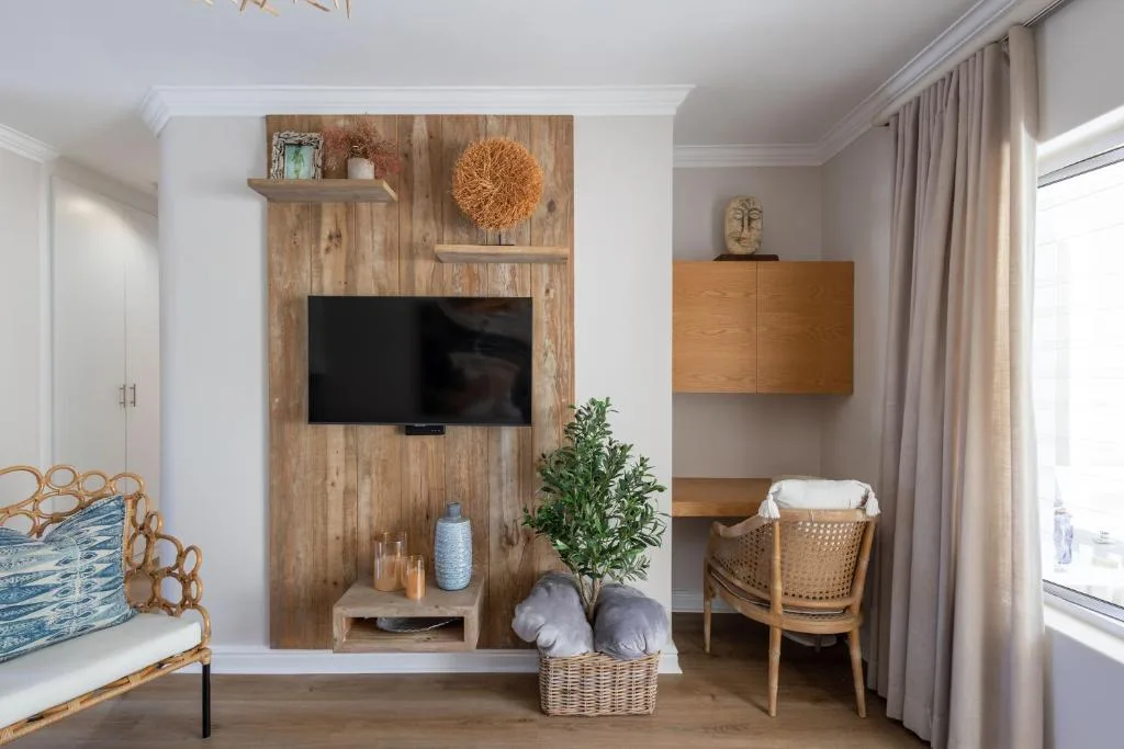 Modern lounge with wooden TV wall, wicker chair, and coastal decor styling