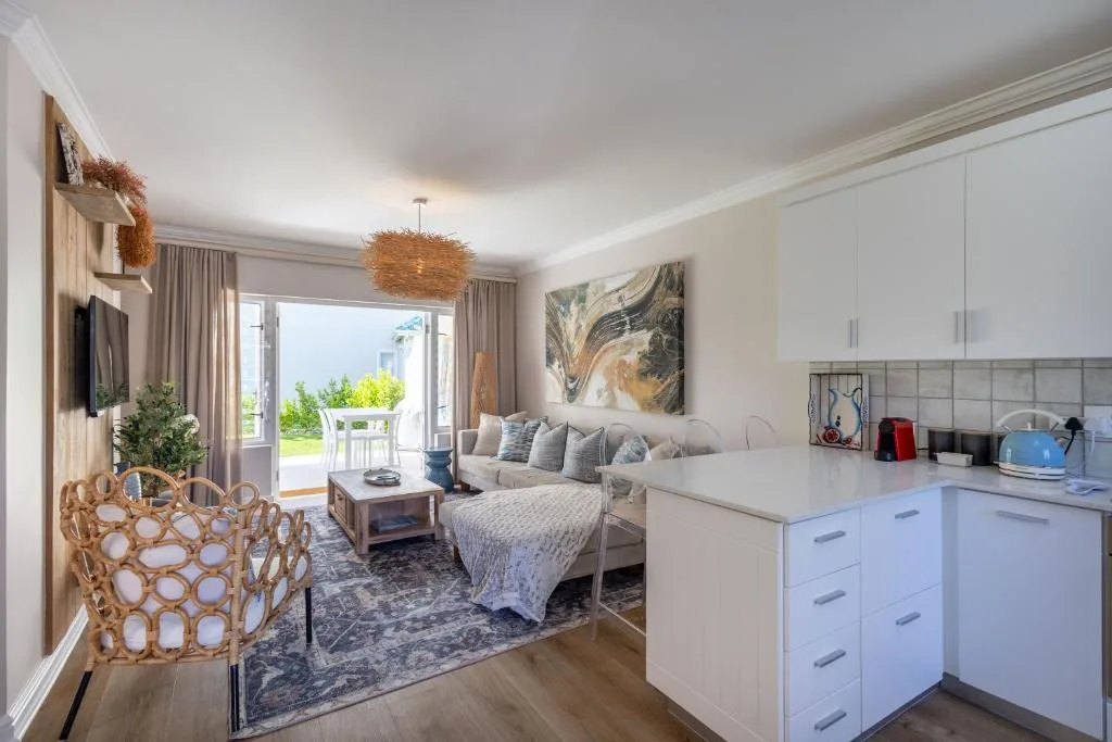 Open-plan living area with sofa, kitchen, and deck access with coastal views