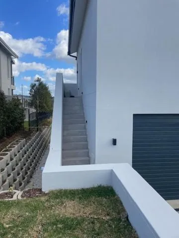 Modern white building exterior with concrete stairs and garden pathway
