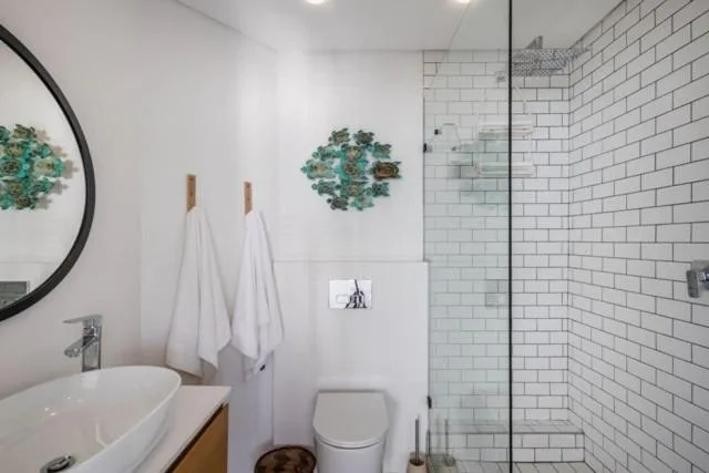 Modern bathroom with white subway tile shower, round mirror, and vessel sink