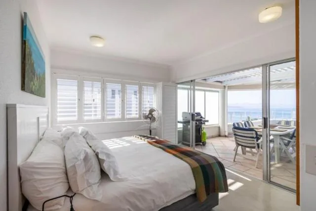 Bright bedroom with ocean views through sliding glass doors to deck