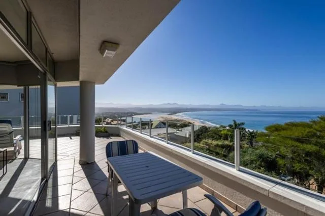 Elevated balcony with ocean and mountain views, outdoor seating table