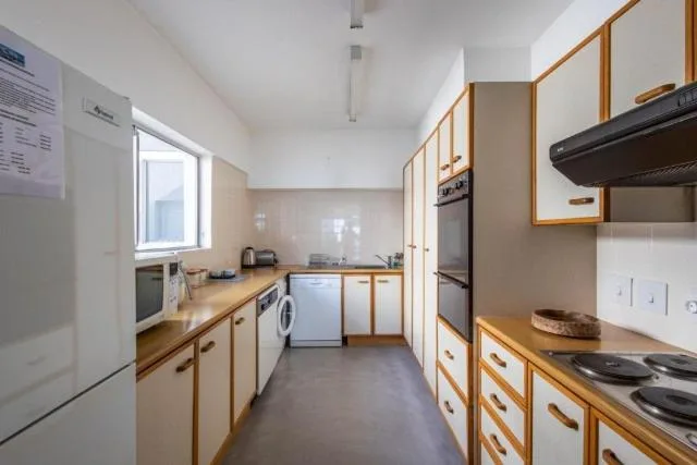 Modern galley kitchen with wooden cabinets, stainless steel appliances, and natural light