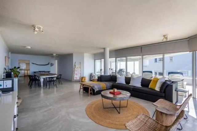 Modern living room with black sofa, round wooden table, and large windows overlooking town