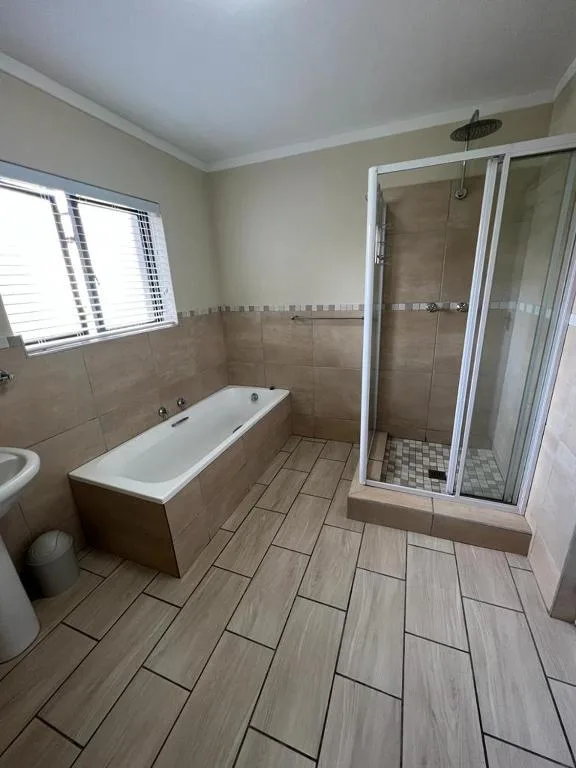 Spacious bathroom with bathtub, walk-in shower enclosure, and wood-look tiling