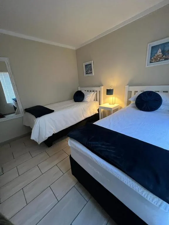 Bright bedroom with two single beds, white headboards, navy accents