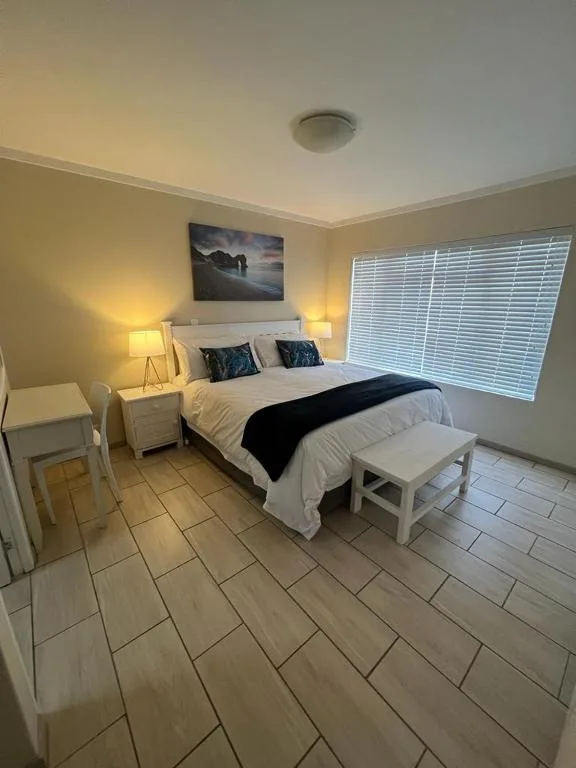 Bright bedroom with queen bed, white bedding, and mountain artwork above headboard