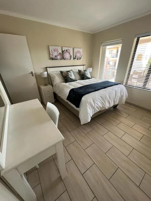 Bright bedroom with queen bed, white bedding, and floral wall art