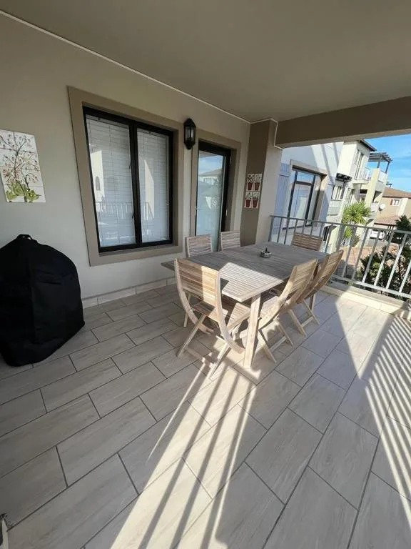 Sunny outdoor balcony with wooden dining table and chairs