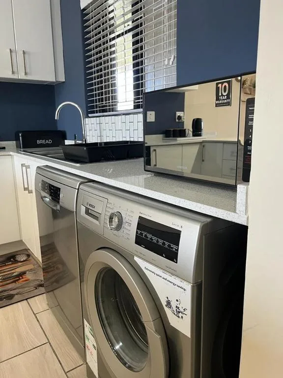 Modern kitchen with washing machine, stainless steel appliances, and granite countertop
