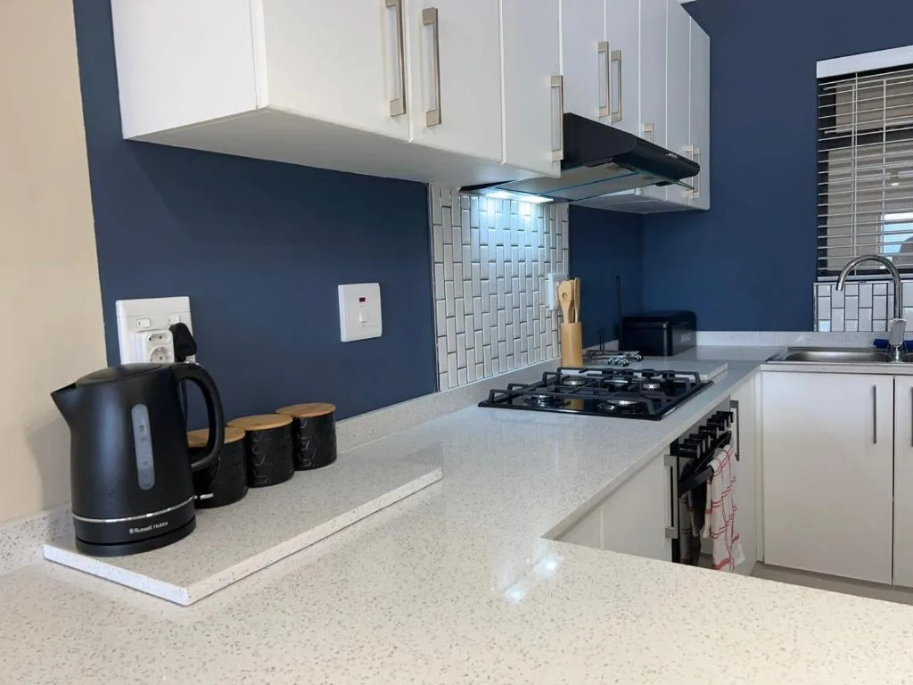 Modern kitchen with gas stove, white cabinetry, and dark blue accent wall