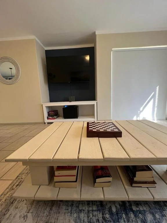 Light wooden lounge with TV mounted above, chess set on table