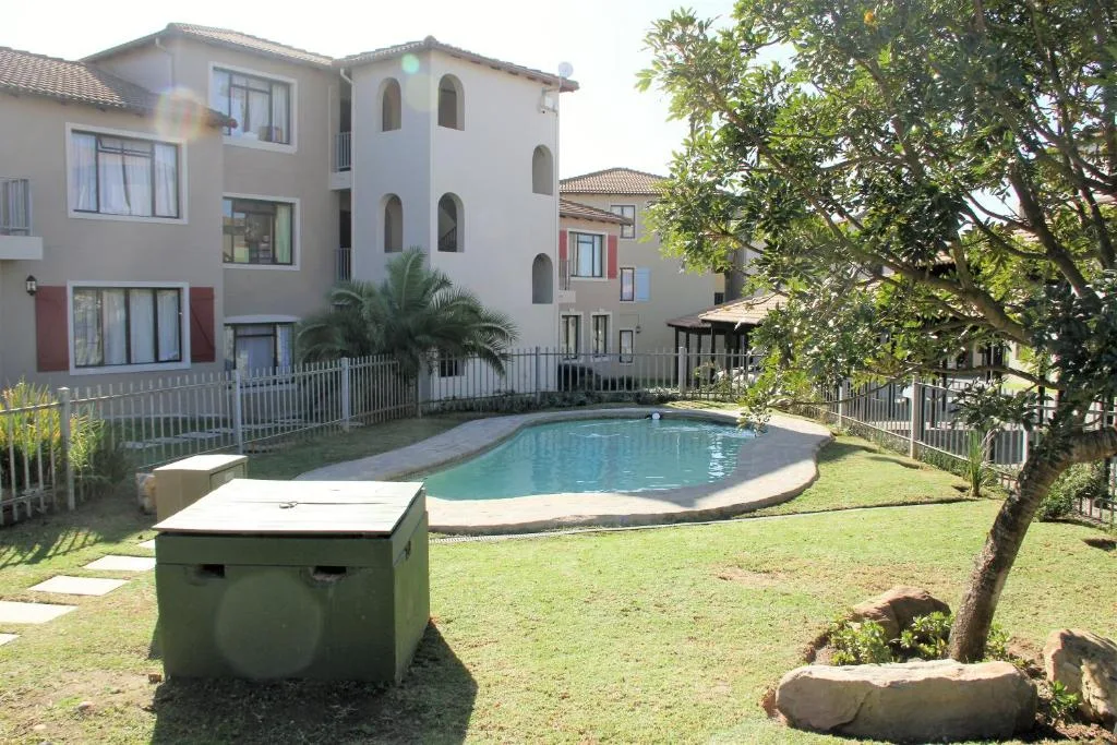 Swimming pool with surrounding garden and residential buildings in background