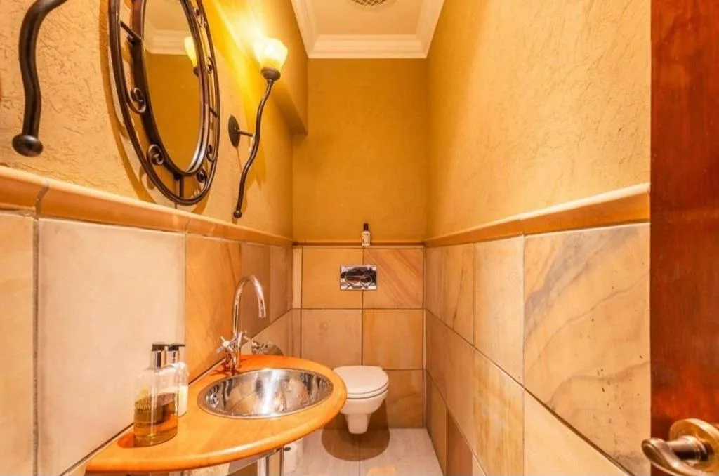 Warm orange bathroom with round stainless steel sink and wall mirror