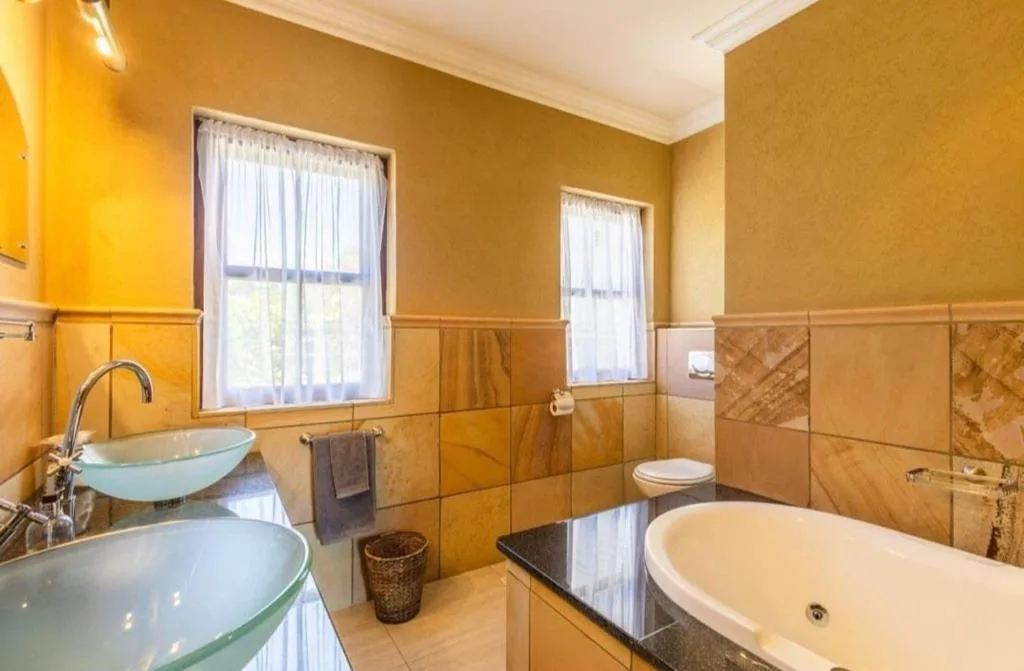 Spacious bathroom with dual vanities, large bathtub, and natural light from windows