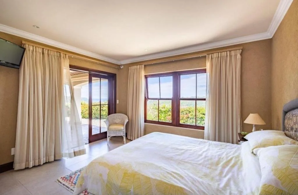 Spacious bedroom with twin beds and scenic garden views through large windows