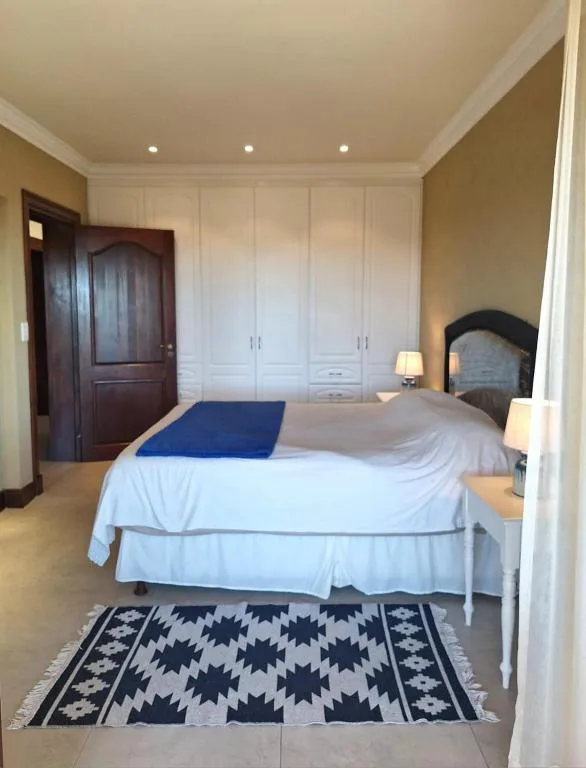 Spacious bedroom with queen bed, built-in wardrobes, and patterned rug