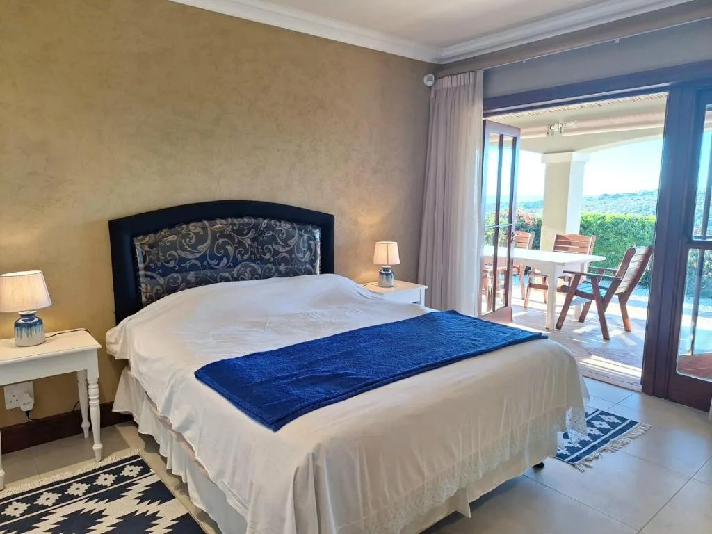 Spacious bedroom with king bed, ocean and mountain views through glass doors