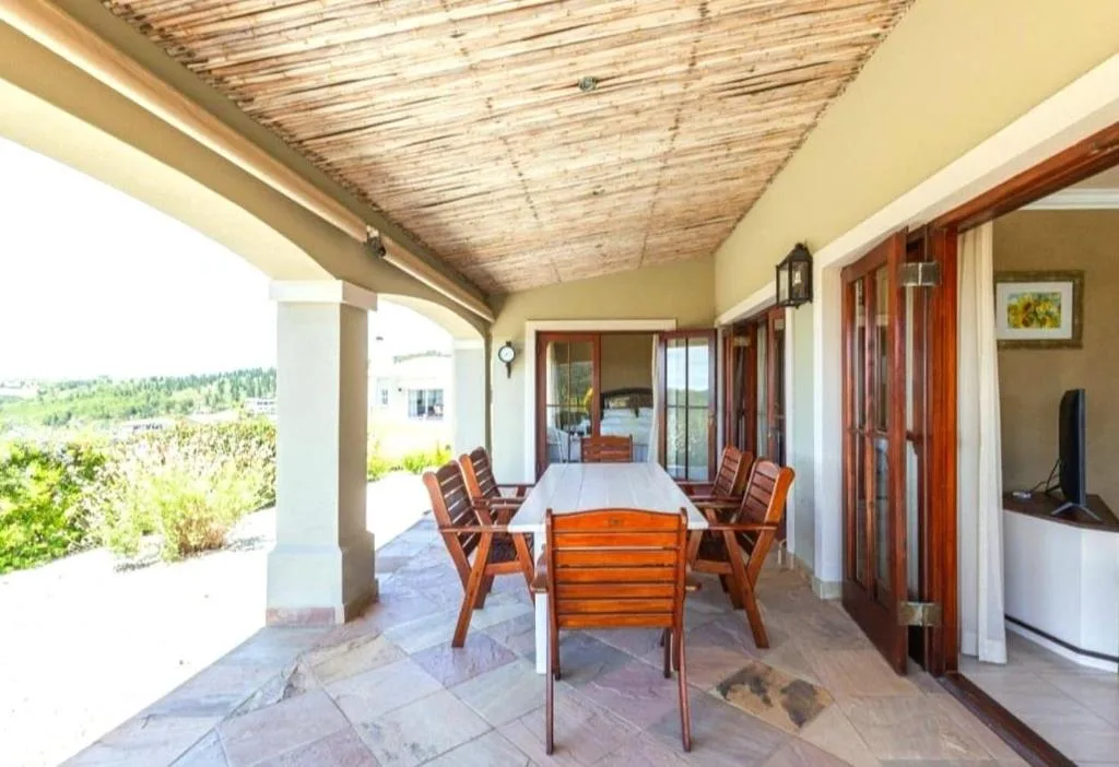 Covered patio with dining table and chairs overlooking garden views