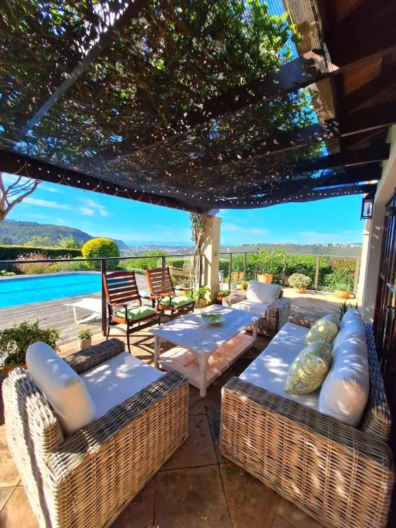 Shaded patio with wicker seating, pool and mountain views beyond