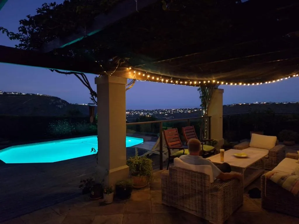 Illuminated poolside deck at dusk with lounge seating and town lights