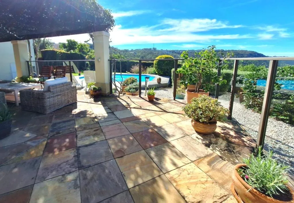 Spacious patio with pool view, potted plants, and mountain vista