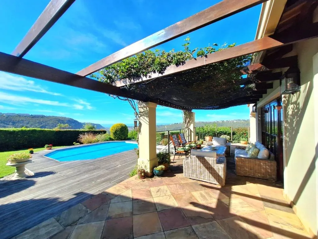 Shaded patio area with pool, lounge furniture, and mountain views