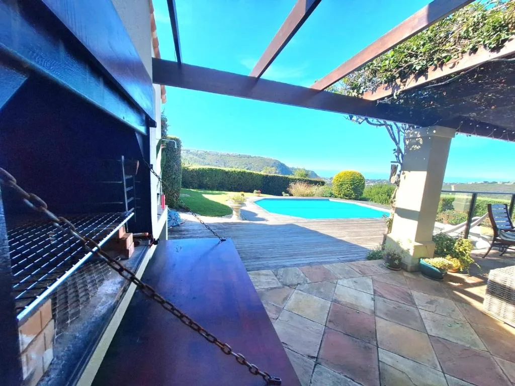 Shaded patio area with braai grill overlooking swimming pool and mountains