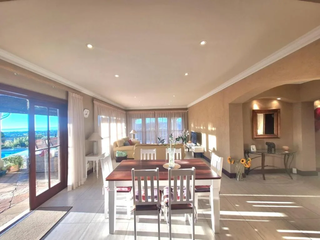 Spacious dining room with wooden table, white chairs, and garden views