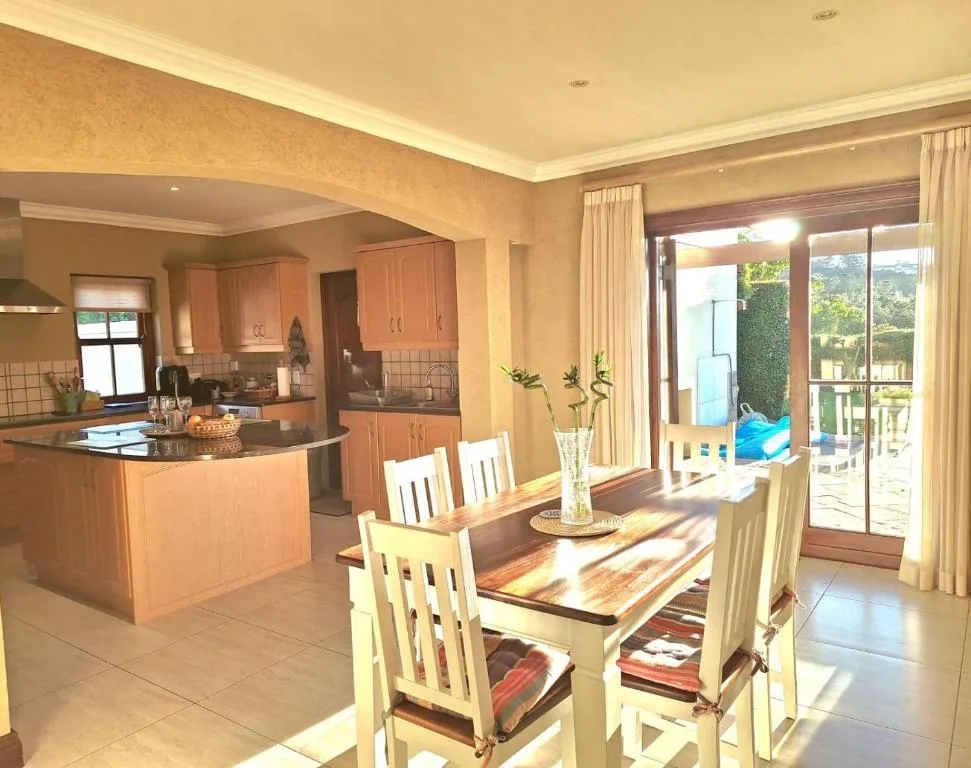 Dining table with cream chairs overlooking kitchen and garden views
