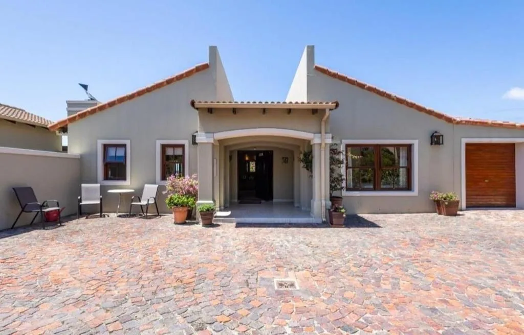 Modern white-rendered cottage with peaked roof and brick paved courtyard entrance