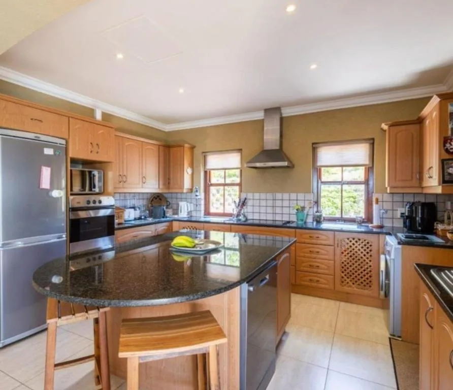 Spacious kitchen with wooden cabinetry, granite island, and modern stainless steel appliances