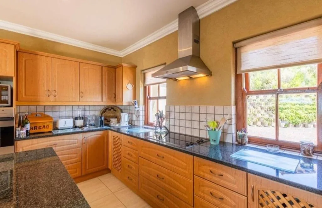 Spacious kitchen with wooden cabinetry, granite counters, and garden views