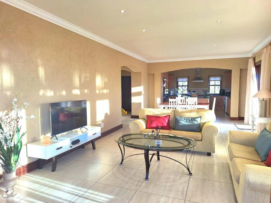 Spacious living room with comfortable sofa, TV, and glass coffee table